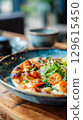 Gourmet Shrimp Pizza with Fresh Greens on Rustic Table. 129615450