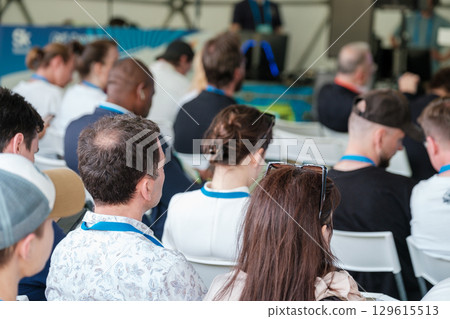 Audience sitting in seminar with speaker in blurred background Audience sitting in seminar with speaker in blurred background 129615513