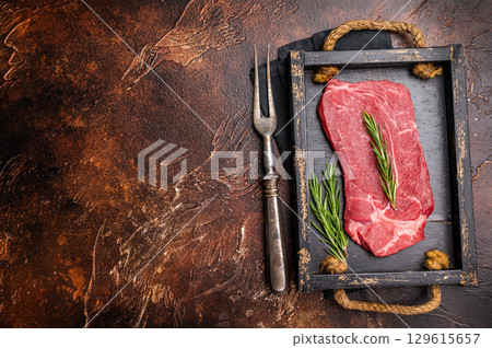 Fresh butchered Raw top sirloin beef steak with rosemary. brown background. top view 129615657