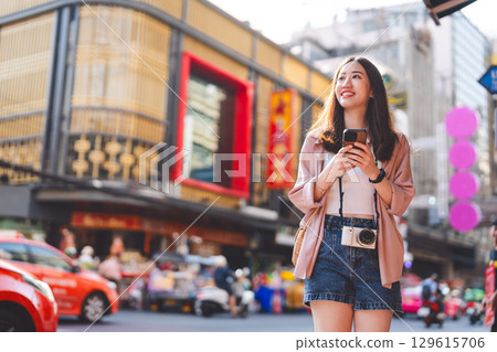 Adult asian woman traveler in urban city using smartphone travel guide 129615706