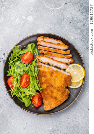 Fried Weiner schnitzel steak, veal breaded meat with salad on a plate. grey background. top view 129615727