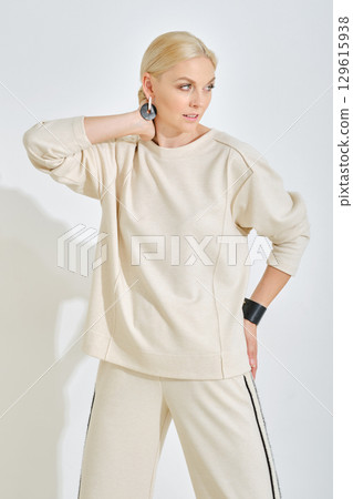 Stylish woman poses in casual fashion outfit in a minimalistic studio setting Stylish woman poses in casual fashion outfit in a minimalistic studio setting 129615938