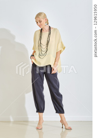 Elegant woman showcasing modern fashion in neutral tones at a bright indoor location Elegant woman showcasing modern fashion in neutral tones at a bright indoor location 129615950