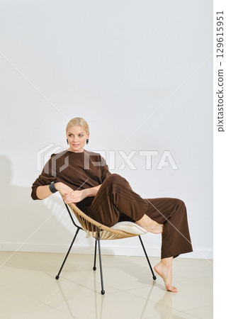 Model poses elegantly on a stylish chair in a minimalistic indoor setting 129615951