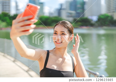 Young adult asian sport woman using smartphone selfie social media rest from running at outdoors Young adult asian sport woman using smartphone selfie social media rest from running at outdoors 129615985