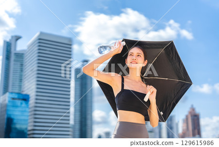 Asian sport woman holding umbrella and water pet bottle prevention from and thirsty heat stroke Asian sport woman holding umbrella and water pet bottle prevention from and thirsty heat stroke 129615986
