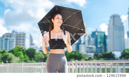 Beautiful young adult asian exercise sport woman holding uv umbrella and mineral water sunny day Beautiful young adult asian exercise sport woman holding uv umbrella and mineral water sunny day 129615999