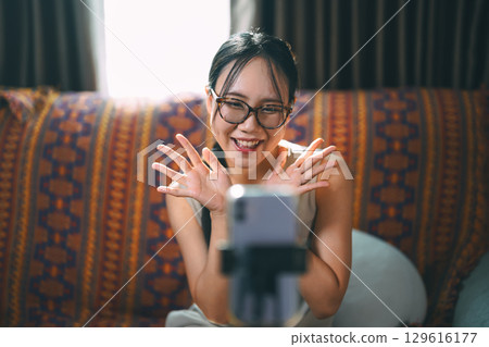 Asian woman influencer using smartphone wireless technology communication customer engagement online marketing 129616177