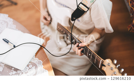 Focus hand of woman on electric guitar chord 129616210