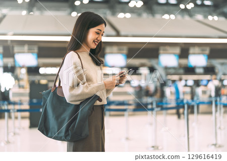 Woman passenger holding passport and boarding pass to transit at international airport terminal 129616419
