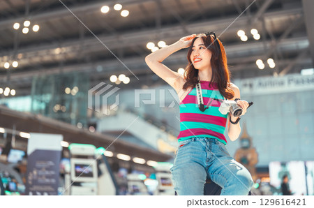 Tourist woman passenger at international airport terminal for holidays travel hand holding camera 129616421