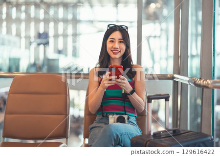 Tourist woman passenger at international airport terminal for holidays travel hand holding camera 129616422