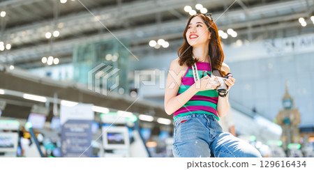 Tourist woman passenger at international airport terminal for holidays travel hand holding camera 129616434
