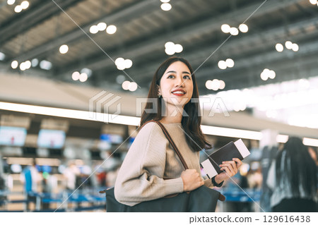 Woman passenger holding passport boarding pass at international airport terminal departure 129616438