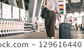 Standing tourist woman with travel luggage waiting at bus terminal for transport on day 129616440