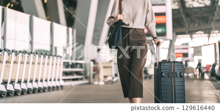 Standing tourist woman with travel luggage waiting at bus terminal for transport on day Standing tourist woman with travel luggage waiting at bus terminal for transport on day 129616440