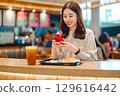 Adult asian woman eating food meal at indoors cafeteria airport terminal 129616442