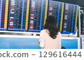 Standing passenger looking flight information status board at international airport terminal 129616444