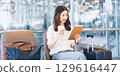 Adult passenger business asian woman sitting with luggage for global trip at airport terminal 129616447