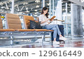 Adult passenger business asian woman sitting with luggage for global trip at airport terminal 129616449
