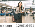 Portrait of standing tourist woman at international airport terminal for departure 129616451