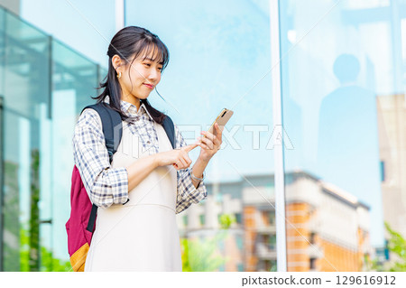 A college student operating a smartphone on campus 129616912