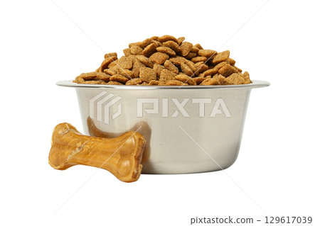 Kibble in a silver bowl with a chew bone nearby, isolated on white, PNG 129617039