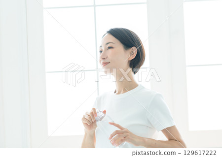 A young woman holding a water bottle and hydrating A young woman holding a water bottle and hydrating 129617222