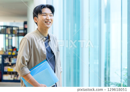 拿著文件的微笑的大學生 129618051