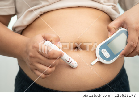 Asian woman injecting herself diabetes injecting insulin in stomach at home. 129618178