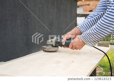 Caucasian male adult using an electric sander for woodwork on outdoor project Caucasian male adult using an electric sander for woodwork on outdoor project 129618323