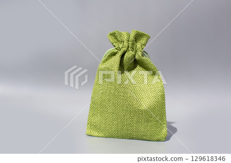 Green fabric gift bag with drawstring on gray background Green fabric gift bag with drawstring on gray background 129618346