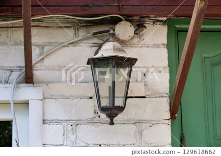 Vintage lantern illuminates rustic home entrance in a serene countryside setting Vintage lantern illuminates rustic home entrance in a serene countryside setting 129618662
