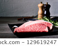 Still life photo of two slices of premium marbled Wagyu beef loin, premium raw meat and seasonings on a black plate 129619247