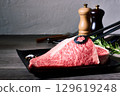 Still life photo of two slices of premium marbled Wagyu beef loin, premium raw meat and seasonings on a black plate 129619248