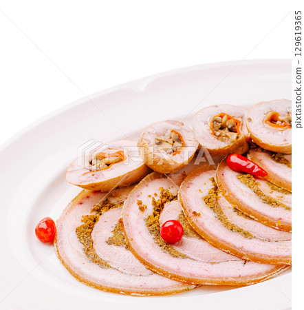 Sliced deli meat with herbs and garnishes served on a white platter 129619365