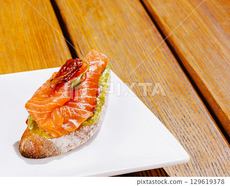 Delicious salmon appetizer served on crispy bread at a cozy cafe Delicious salmon appetizer served on crispy bread at a cozy cafe 129619378