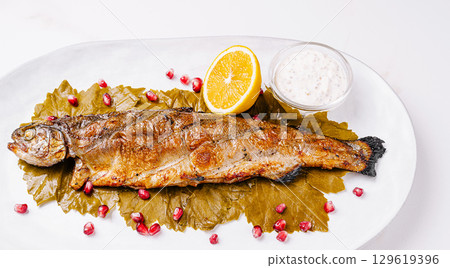 Grilled trout served on a platter with garnishes and dipping sauce Grilled trout served on a platter with garnishes and dipping sauce 129619396