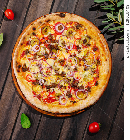 Delicious pizza topped with cheese, vegetables, and meat on a wooden table Delicious pizza topped with cheese, vegetables, and meat on a wooden table 129619408