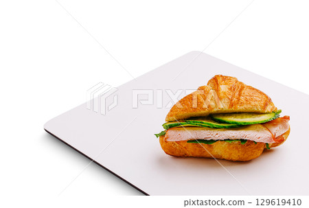 Fresh croissant sandwich with ham and vegetables on a clean surface 129619410