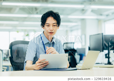 前往一台計算機的年輕商人在辦公室 129619416