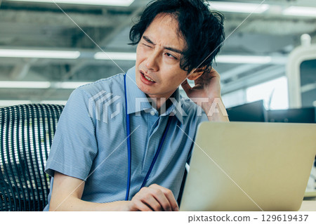 A man who is worried while looking at a computer A man who is worried while looking at a computer 129619437