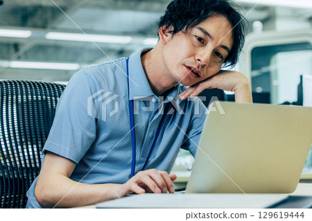 A man who is worried while looking at a computer A man who is worried while looking at a computer 129619444
