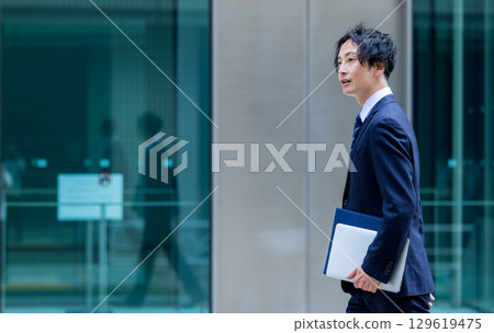 Businessman walking on a sidewalk Businessman walking on a sidewalk 129619475