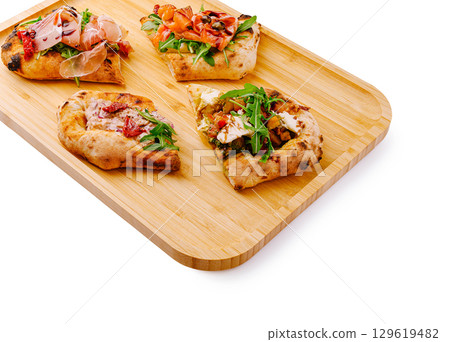 Artisan flatbreads with fresh toppings served on a wooden tray Artisan flatbreads with fresh toppings served on a wooden tray 129619482