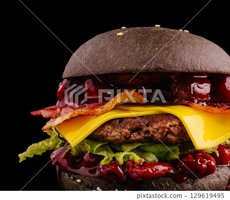 Unique black burger with cheese and bacon served on dark background 129619495