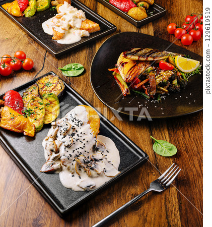 Delicious gourmet dishes served on elegant black plates at a modern restaurant Delicious gourmet dishes served on elegant black plates at a modern restaurant 129619519