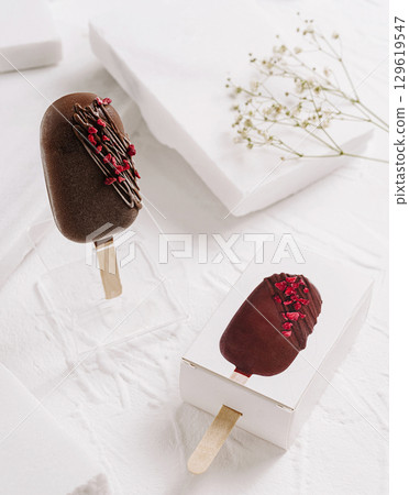 Delicious chocolate popsicles with raspberry topping on white background Delicious chocolate popsicles with raspberry topping on white background 129619547