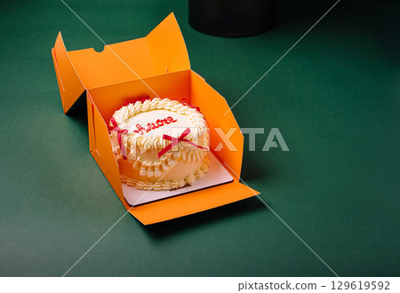 Celebration cake in vibrant orange box on green surface 129619592