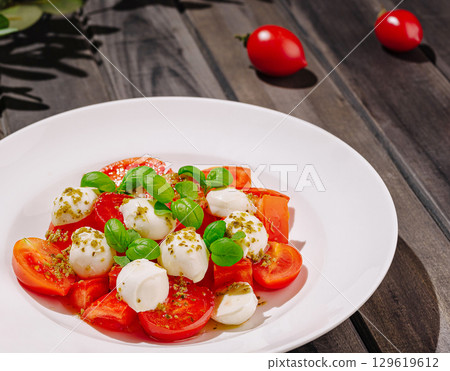 Fresh mozzarella and tomato salad with basil on wooden table 129619612